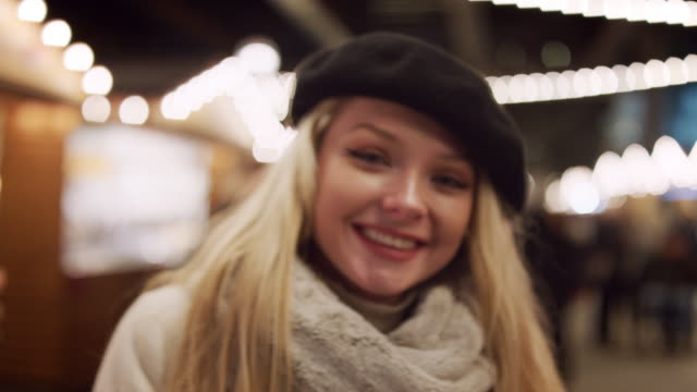 Porträt-von-lächelnden-Frau-genießen-Weihnachtsmarkt-bei-Nacht