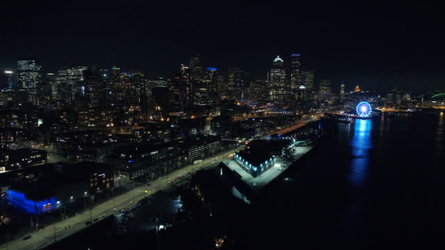 Vista-de-helicóptero-de-Seattle-Waterfront-en-la-noche-en-vibrante-iluminación