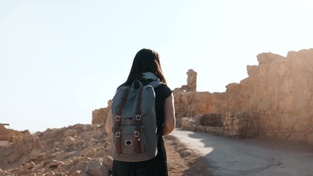 Nettes-Mädchen-mit-Rucksack-Spaziergänge-entlang-der-antiken-Ruinen.-Ziemlich-europäischen-weibliche-Touristen-erforscht-Israel-Masada-Festung.-4K