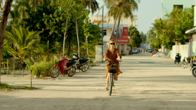 Hermosa-mujer-con-vestido-paseos-en-bicicleta-en-el-camino-a-través-del-auténtico-pueblo-pequeño.-Naturaleza-de-Asia-del-sur,-bosques-escénico-por-la-carretera.