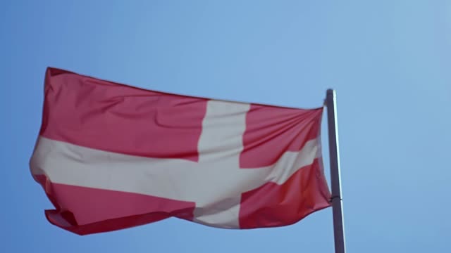 Bandera-de-Dinamarca-ondeando-en-el-viento-con-cielo-azul
