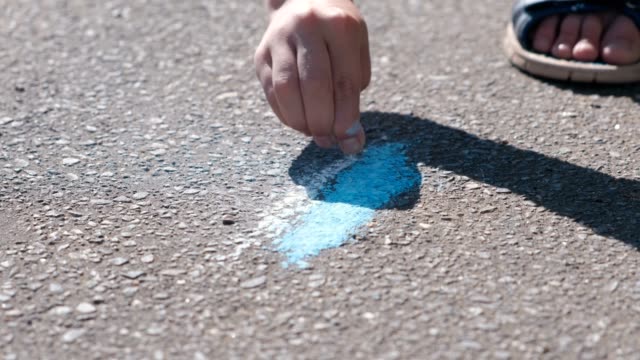 Boy-draws-with-blue-chalk-on-the-asphalt.-Close-up-hands.