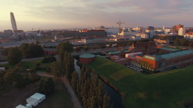 Luftaufnahme-von-Malmö-Stadtbild-bei-Sonnenuntergang.-Drohne-Schuss-fliegt-über-\"Malmohus\"-in-Schweden,-Turning-Torso-Gebäude-im-Hintergrund