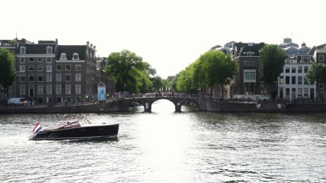 Oldtimer-Boot-segelt-in-ikonische-Kanal-mit-traditionellen-Brücke-in-Amsterdam,-Holland-Europa