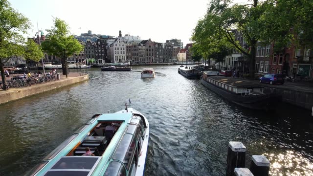 iconic-Amsterdam-canal-with-cruise-tour-boat-sailing-under-the-bridge-in-Amsterdam,-Holland-Europe