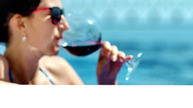 Medium-close-up-portrait-relaxing-woman-in-sunglasses-sunbathing-enjoying-at-pond-drinking-red-wine