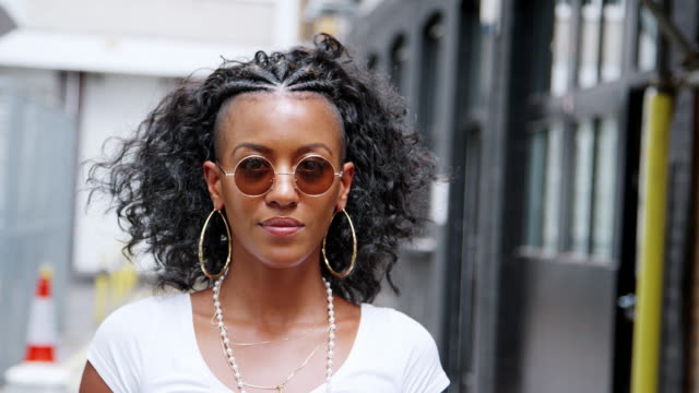 Fashionable-young-black-woman-turning-and-looking-to-camera-over-her-round--sunglasses,-close-up