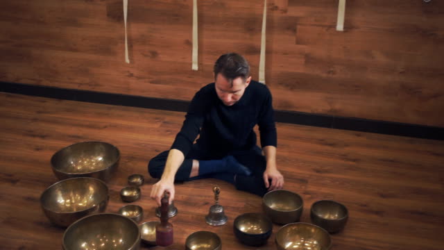 A-man-sits-in-the-lotus-position-and-plays-on-the-Tibetan-singing-bowls