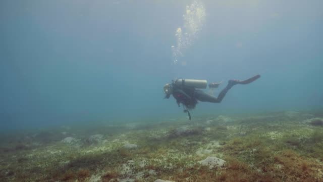 Taucher-am-Meeresboden-schweben-und-winken-Hand,-Kamera,-Unterwasser-Blick