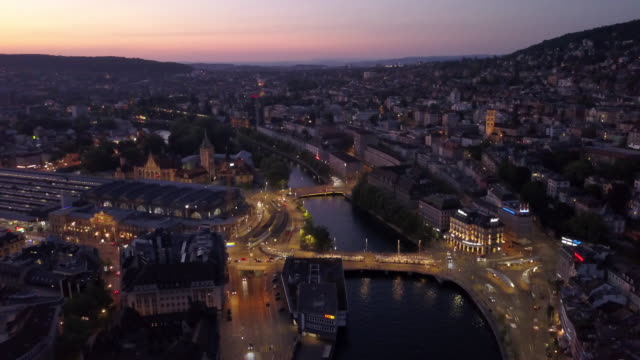 puesta-de-sol-iluminada-Zurich-centro-ciudad-orilla-aérea-panorama-4k-Suiza