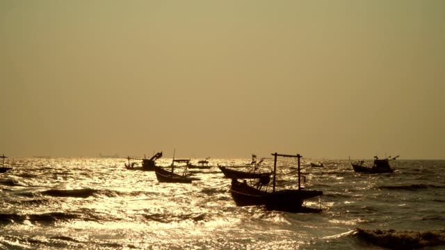 Viele-kleine-Fischerboote-Südostasiens-befinden-sich-im-Fischerhafen-der-Dorfbewohner.-Das-goldene-Licht-reflektiert-das-Wasser-während-des-Sonnenuntergangs.