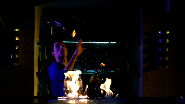 Professional-bartender-making-cool,-amazing-tricks-with-two-bottles-standing-behind-the-bar,-catching-on-arm,-throwing-up,-fire-show,-slow-motion