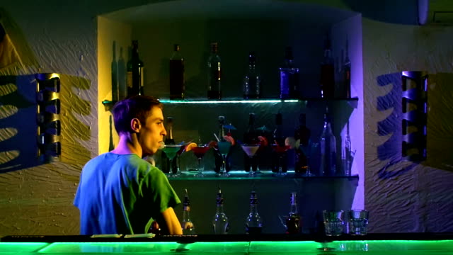 Professional-bartender-making-cool,-amazing-tricks-with-two-glasses,-shaker-and-bottle-standing-behind-the-bar,-catching-on-elbow,-throwing-up,-slow-motion