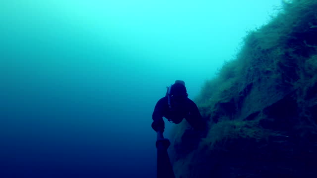 Freedivers-explorar-un-lado-de-un-submarino-del-acantilado-en-una-cantera
