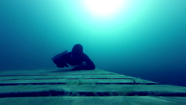 Freediver-gatear-Underwater-en-una-plataforma-de-madera