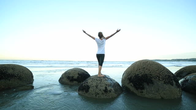 Female-exercises-yoga-on-a-boulder-by-the-sea