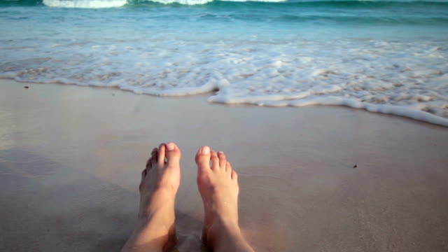 Mädchen-sitzt-am-Strand-und-lassen-Sie-Ihre-Füße-nass