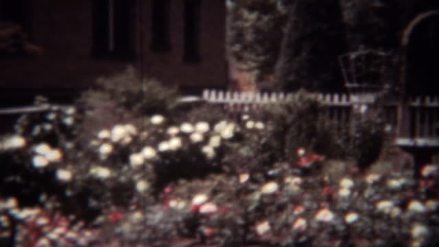 1939:-mujer-jardinería-flores-rosa-patio-con-bonete-blanco.