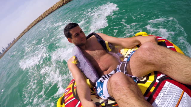 Mann-sitzt-im-aufblasbaren-Ring-mit-einem-Boot-im-Wasser-geschleppt-und-Aufnahme-selbst-mit-Go-Pro-Kamera