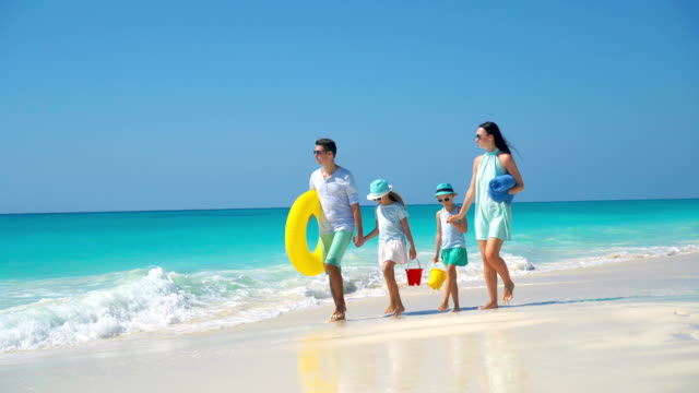 Glückliche-schöne-Familie-von-vier-an-einem-tropischen-Strandurlaub