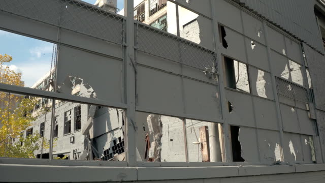 CLOSE-UP:-Zerbrochene-Fensterscheiben,-beschädigte-Fassade-&-bröckelnden-Mauern-in-verlassenen-Fabrik