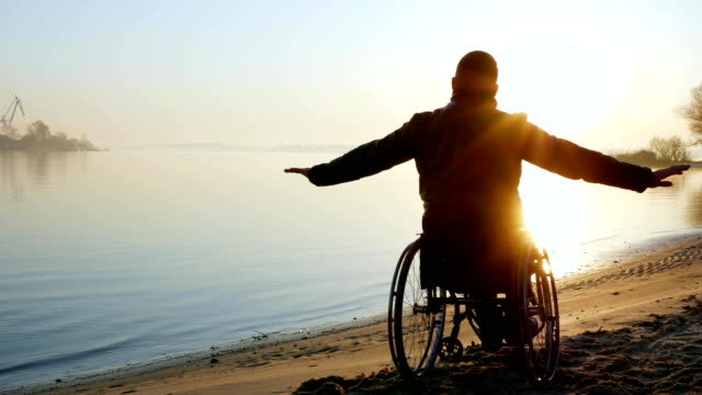 Krüppel-Person-Hände-hoch,-Sonnenuntergang-am-Rollstuhl,-einsam-auf-deaktiviert