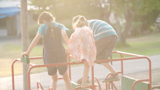 Drei-Kinder-spielen-auf-einem-öffentlichen-Spielplatz-während-des-Sonnenuntergangs