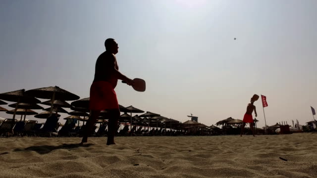 Zwei-Männer-Silhouette-spielen-Beach-Tennis-am-Strand