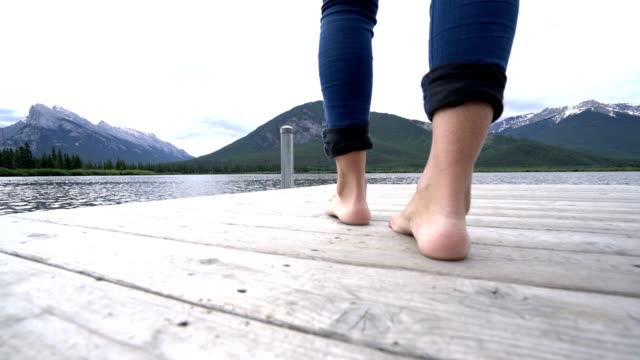 Frau-die-Füße-zu-Fuß-am-Steg-über-dem-Lake,-Kanada