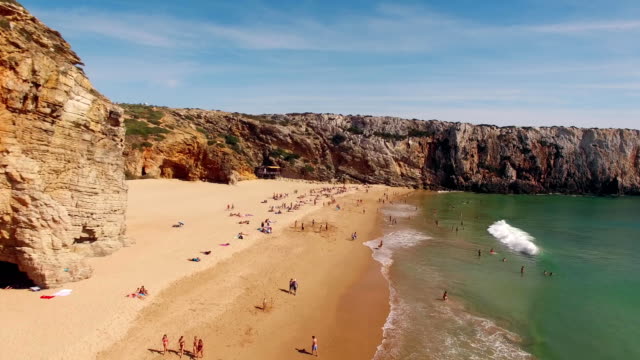Happy-people-rest-on-a-beautiful-sandy-beach-in-Portugal,-Praia-do-Beliche,-Sagres,-aerial-view