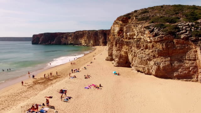 Group-of-people-resting-on-beach-in-Portugal,-Praia-do-Beliche,-Sagres,-aerial-view