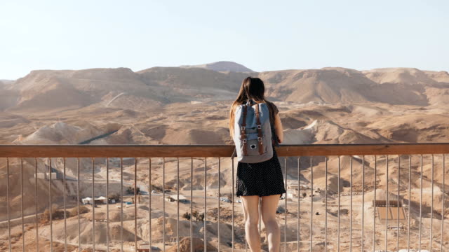 Frau-mit-Rucksack-schaut-an-massiven-Blick-auf-die-Berge.-Ziemlich-kaukasische-Mädchen-genießt-unglaubliches-Wüste-Panorama.-Israel-4K