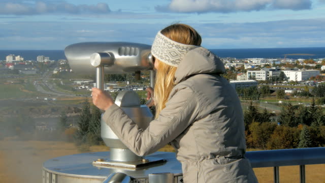 junge-Touristen-Mädchen-sucht-in-einem-stationären-Teleskop-auf-Reykjavik-im-sonnigen-Tag