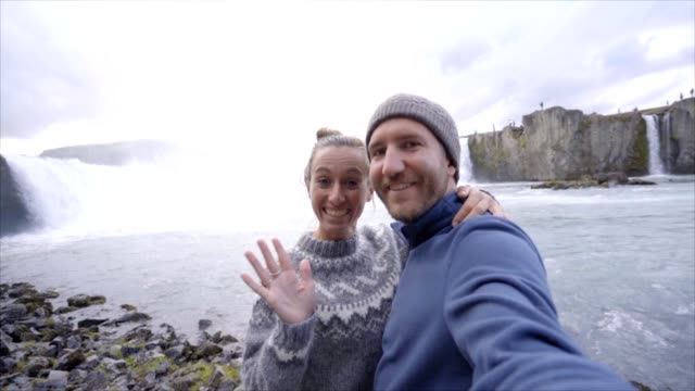 Reisen-paar-Spaß-Selfie-Aufnahme-von-Godafoss-Wasserfall-auf-Island-mit-Smartphone.-Die-Menschen-Sie-besuchen-berühmte-Sehenswürdigkeiten-und-Wahrzeichen-auf-Route-1
