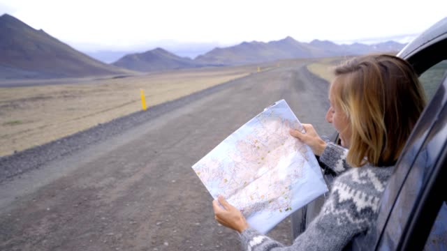 Mujer-joven-en-coche-mirando-el-mapa,-ruta-viaje-concepto-vacaciones---4K