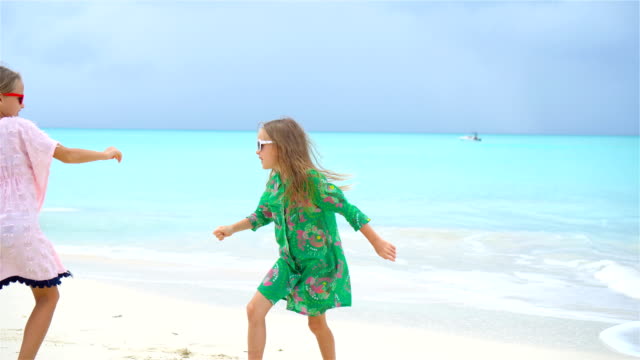 Dos-niñas-felices-tienen-un-montón-de-diversión-en-playa-tropical-tocando-juntos