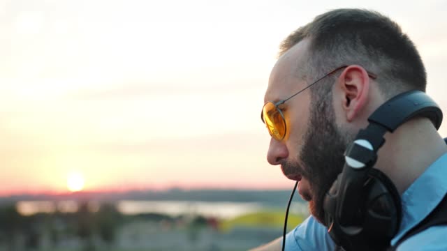 Profil-von-modischen-DJ-mit-Kopfhörer-und-Sonnenbrille-Musikgenuß-am-Sommerfest-auf-dem-Dach