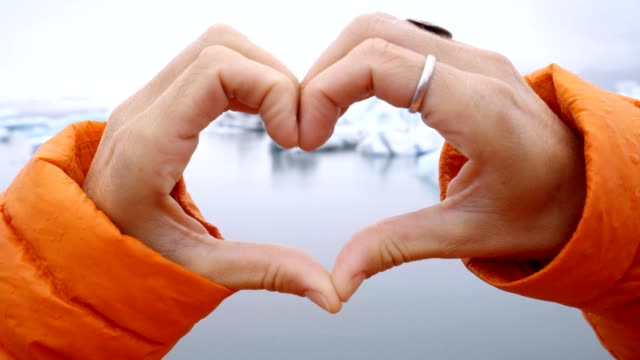 Close-up-on-heart-shape-finger-frame-on-glacier-lagoon-in-Iceland-showing-love-and-respect-to-the-environment