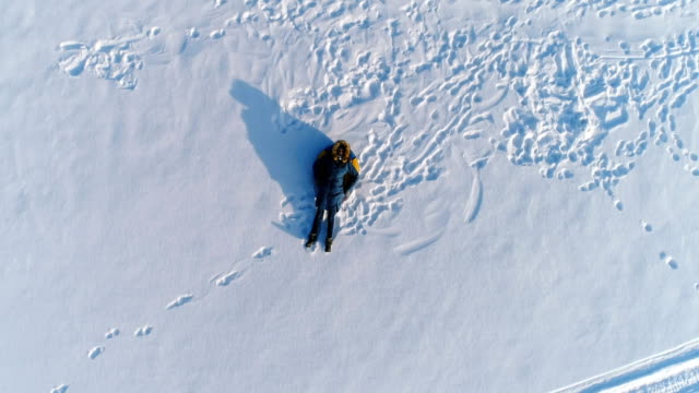 Woman-is-laying-on-tubing-in-the-snow.-Camera-slowly-rising.-Aerial-footage.