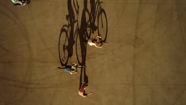 Children-riding-race-on-wheeled-vehicles-cast-long-shadows.-Top-view