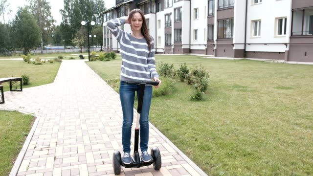 Beautiful-brunette-woman-is-rolling-on-gyro-scooter-near-the-home.