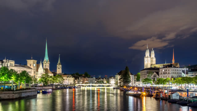 Zurich-Switzerland-time-lapse-4K,-city-skyline-night-timelapse-at-Limmat-River-with-Grossmunster-and-Fraumunster-Church