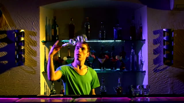 Professional-bartender-making-cool-tricks-with-two-glasses,-shaker-and-bottle-standing-behind-the-bar,-catching-on-elbow,-throwing-up,-slow-motion