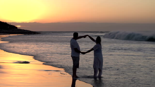 Par-disfruta-de-románticos-abrazar-en-la-playa-en-silhouette,-Sudáfrica