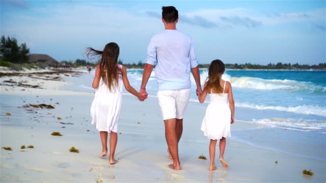 Family-walking-on-white-beach-on-caribbean-island-in-the-evening