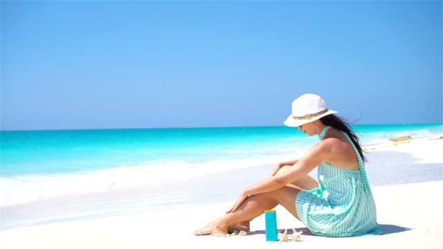 Junge-Frau-Creme-auf-ihre-glatte-gebräunte-Beine-am-tropischen-Strand
