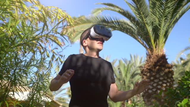 Video-of-man-exploring-virtual-reality-in-tropical-garden-in-4k