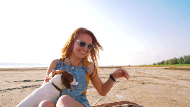 young-stylish-hipster-playing-dog-puppy-jack-russell-on-the-beach,-slow-motion