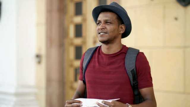 African-american-tourist-man-looking-into-paper-city-map-exploring-sightseeings-during-travelling-in-Europe
