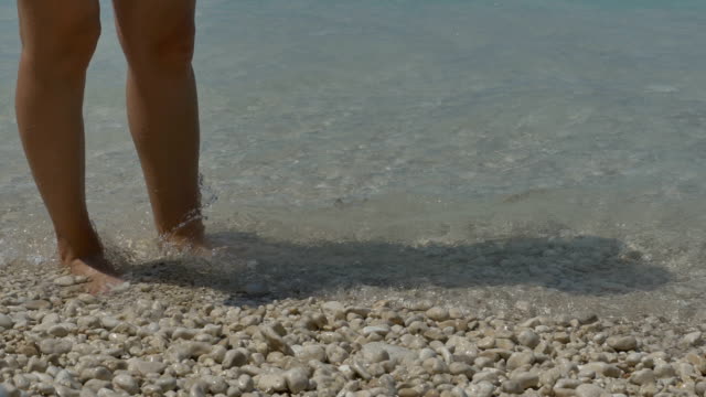 Mädchen-Füße-spritzte-von-Wellen